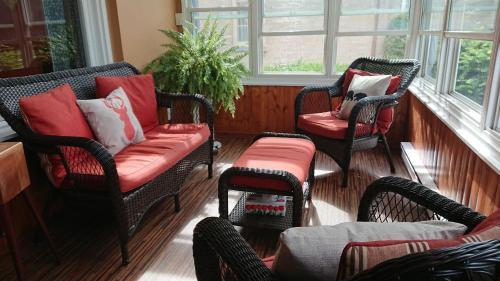 a porch with three chairs and a couch and windows at Colborne Bed and Breakfast in Goderich