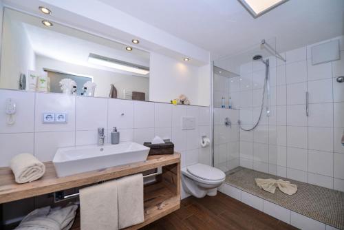 a bathroom with a sink and a shower and a toilet at Sonnenbichl Hotel am Rotfischbach in Fischen