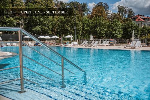 a swimming pool with blue water and chairs and umbrellas at Grand Hotel Rogaška Premium in Rogaška Slatina