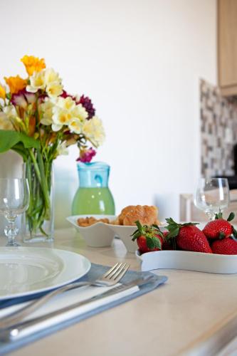 a table with strawberries and flowers and a plate of food at Villa Dina with private Juccuzi in Perissa