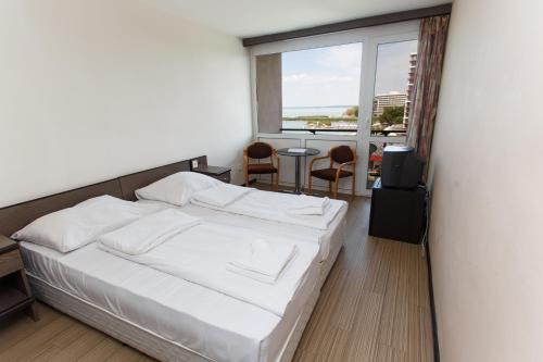 Schlafzimmer mit einem Bett, einem Tisch und einem Fenster in der Unterkunft Hotel Hungária in Siófok