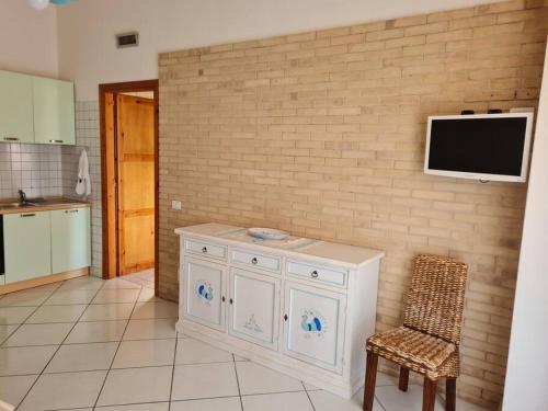 a kitchen with a white cabinet and a tv on a brick wall at Casa Alessandro in Villasimius