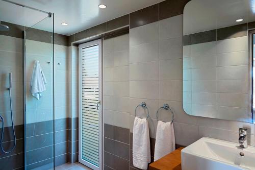 een badkamer met een wastafel en een glazen douche bij Helion Apartments in Gouvia