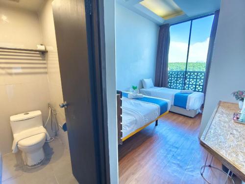 a bedroom with a bed and a toilet and a window at The Riverbank Hotel By MRVJ Business in Kuantan