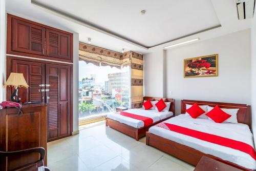 a bedroom with two beds with red pillows and a window at OYO 265 An Thinh Loc in Danang