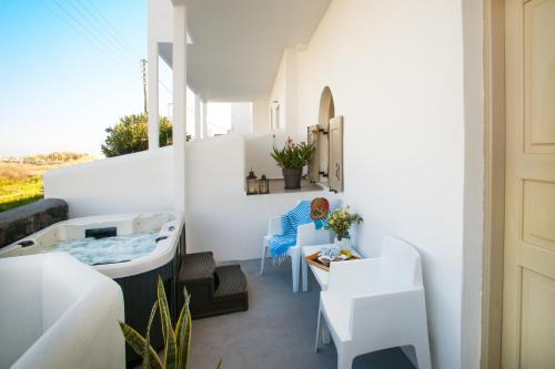 a small balcony with a tub and a table and chairs at Villa Dina with private Juccuzi in Perissa