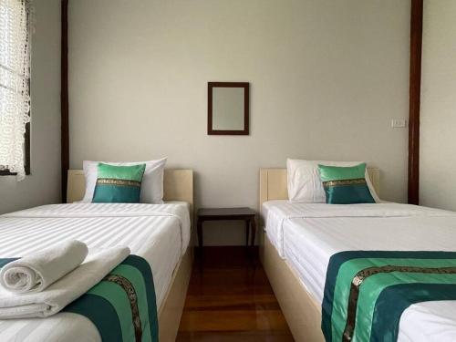 a bedroom with two beds with green and white sheets at GrandmaD in Chiang Rai