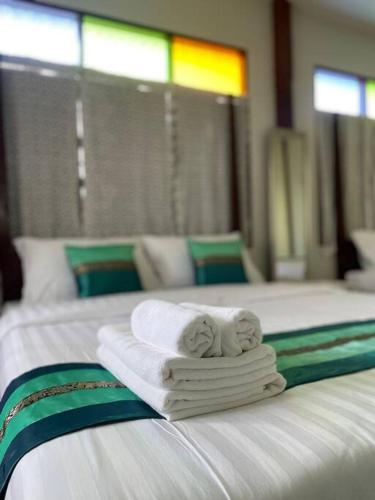 two folded towels sitting on top of a bed at GrandmaD in Chiang Rai