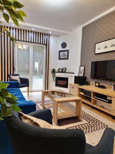 uma sala de estar com cadeiras azuis e uma televisão em Apartment Roosevelt em Belgrado