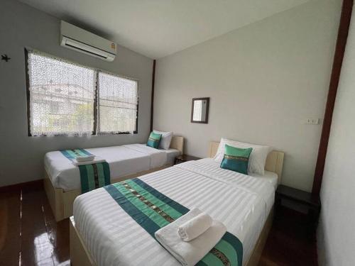 a bedroom with two beds and a window at GrandmaD in Chiang Rai