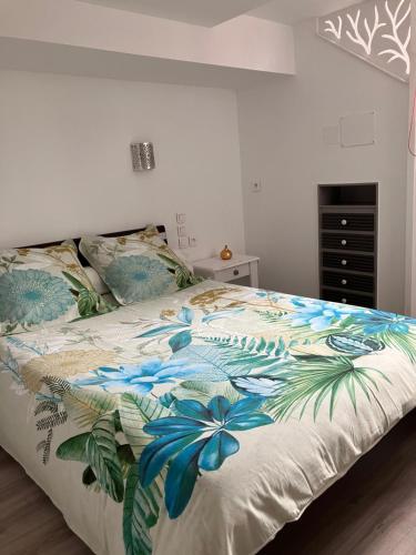 1 dormitorio con 1 cama con colcha de flores en 2 pièces rez-de-jardin dans maison avec piscine en Villeneuve-Loubet