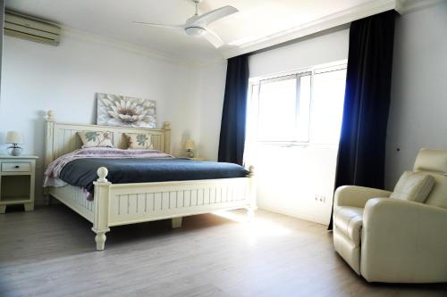 1 dormitorio con 1 cama, 1 silla y 1 ventana en Villa Seaview Suncoast Luxury, en Málaga