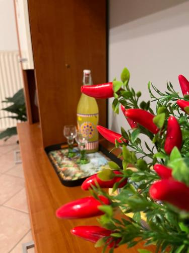 a table with a bottle and a plant with red flowers at DIP IN SICILY in Lentini