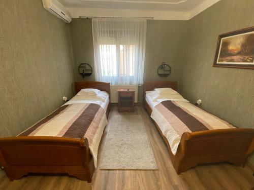 two beds in a small room with a window at Fehér Hattyú Panzió in Orosháza