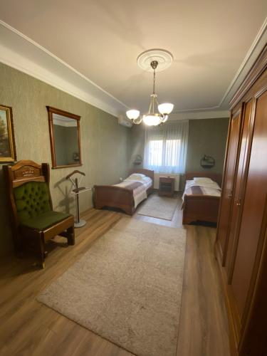 a bedroom with two beds and a chair and a mirror at Fehér Hattyú Panzió in Orosháza