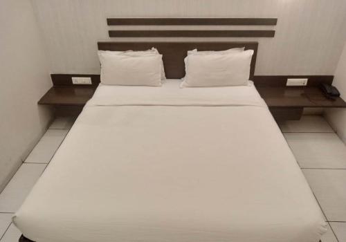 a bed with white sheets and pillows in a room at Hotel Kanan in Ahmedabad