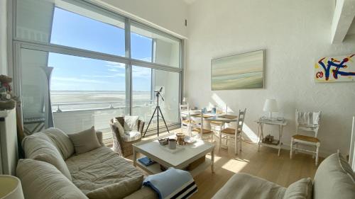 - un salon avec un canapé, une table et une grande fenêtre dans l'établissement Les Pieds dans l'Eau, vue sur la baie pour 6 pers, au Crotoy