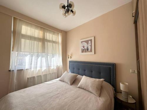 a bedroom with a bed with a blue headboard and a window at Modern building on Rustaveli Ave in Okrokana