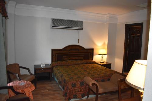 a bedroom with a bed and a chair and a lamp at Grand Regency Hotel in Pothi