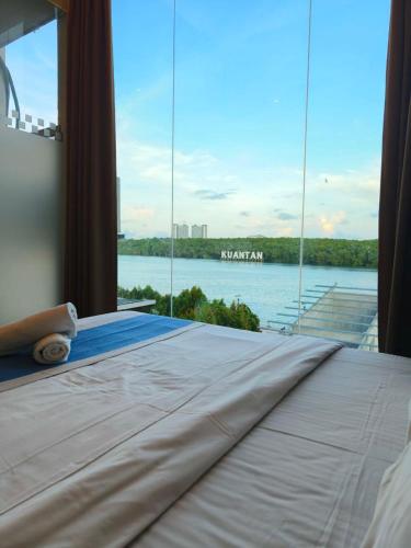 a bedroom with a large bed with a view of the water at The Riverbank Hotel By MRVJ Business in Kuantan