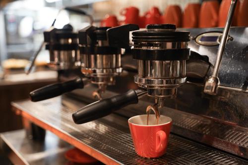 a coffee machine pouring coffee into a red cup at Home Hotel Folketeateret in Oslo