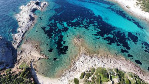 una vista aérea de una playa de agua azul en Camping Tonnara, en Cala Sapone