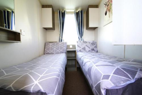 2 camas en una habitación pequeña con ventana en Lovely 2-Bed Static Caravan in Rhyl en Rhyl