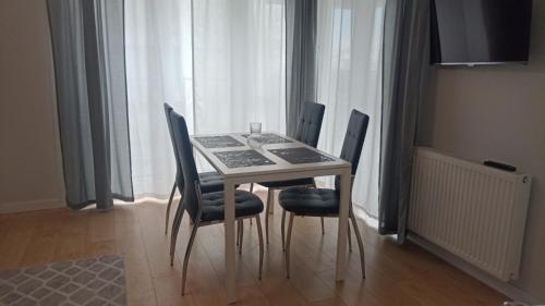 mesa de comedor con 4 sillas frente a una ventana en Apartament targowy, en Poznan