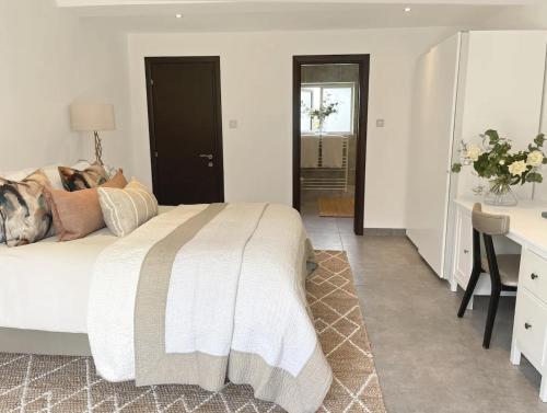 a white bedroom with a bed and a desk and a desk at The Barn in Chichester