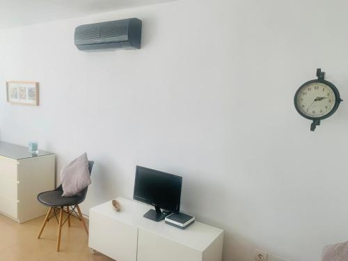 Zimmer mit einem TV, einem Stuhl und einer Uhr in der Unterkunft Apartamento La Quinta in La Cala del Moral