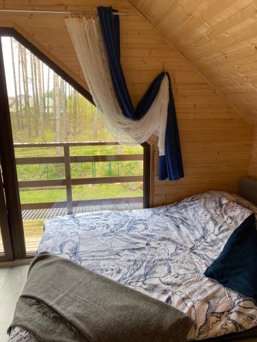 a bed in a log cabin with a window at Jarzębinowy Zakątek in Kopalino