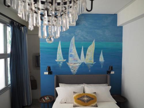 a bedroom with a blue wall with a painting of sailboats at Seamoon House in Tainan
