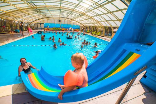 a baby on a slide in a swimming pool at Papillon Country Resort in Denekamp