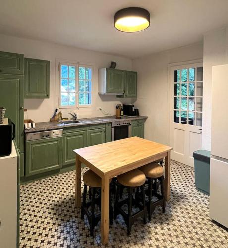 a kitchen with green cabinets and a wooden table at Chalet St-François in Ollon