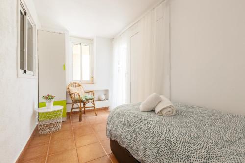 a white bedroom with a bed and a chair at Tres Terrazas in Sant Pere de Ribes