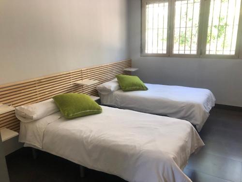 2 Betten mit grünen Kissen in einem Zimmer in der Unterkunft casa con vistas en Agost in Agost