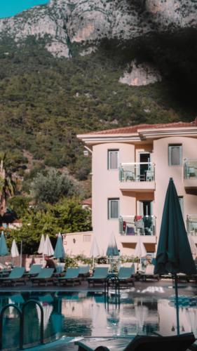 a hotel with a swimming pool with chairs and umbrellas at Belcehan Hotel in Oludeniz