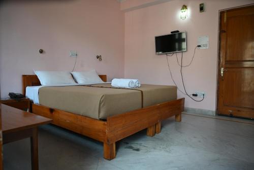 a bedroom with a bed and a tv on the wall at Hotel Atul Regency in Rāmpur