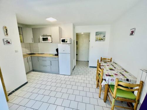 une cuisine avec une table, des chaises et un réfrigérateur dans l'établissement Appartement 6 pers. - Proche port et plage avec terrasse & parking privé - Cap d'Agde - FR-1-723-68, au Cap d'Agde