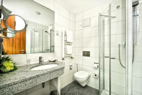 a bathroom with a toilet, sink, and shower at Hotel Central in Nuremberg