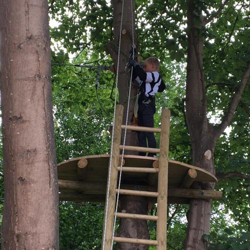 a boy on a ladder in a tree house at Nivå Camping & Cottages in Nivå