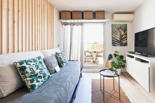 ein Wohnzimmer mit einem Sofa und einem Tisch in der Unterkunft La Casita - Studio Confort avec Terrasse et Parking privé - La Grande Motte, Montpellier in La Grande-Motte