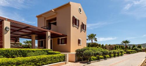 a house with bushes and trees in front of it at Gold Crest Home in Drapanias beach, Nopigia in Kissamos