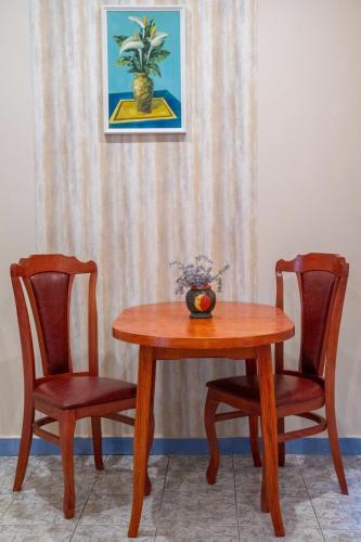 una mesa de madera con 2 sillas y un jarrón. en Апартамент Орловска, en Gabrovo