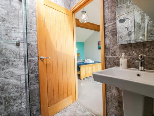 La salle de bains est pourvue d'un lavabo et d'une douche. dans l'établissement Bluebell Cottage, à Ulverston