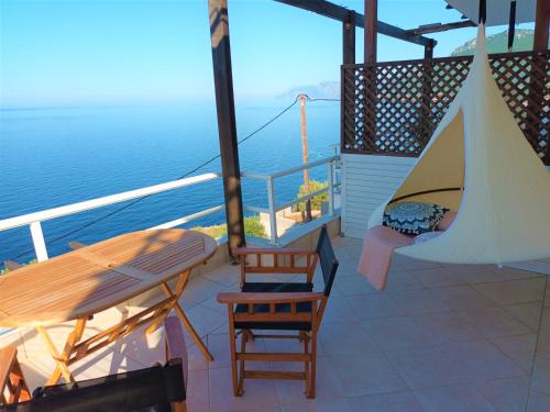 een balkon met een tafel en stoelen en de oceaan bij Dream apartments limnionas in Limniónas