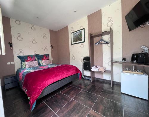 a bedroom with a bed with a red blanket at Villa de l’Eguille in LʼÉguille