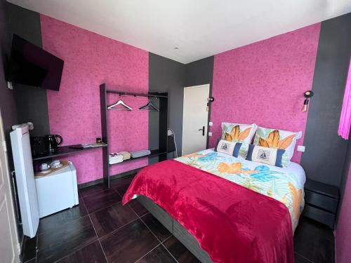 a bedroom with pink walls and a large bed at Villa de l’Eguille in LʼÉguille
