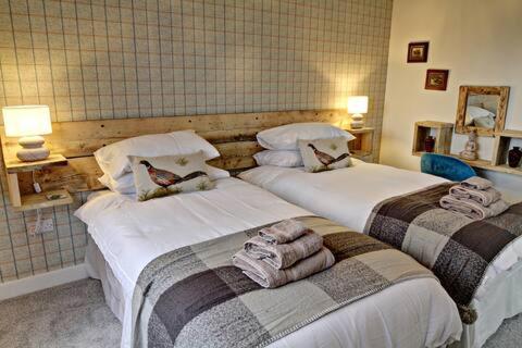 two beds in a hotel room with towels on them at Byre 1 in Stirling