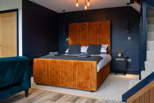 蘭登尼奧冷的住宿－Plas Coch Luxury Barn，一间卧室配有一张大床和木制床头板